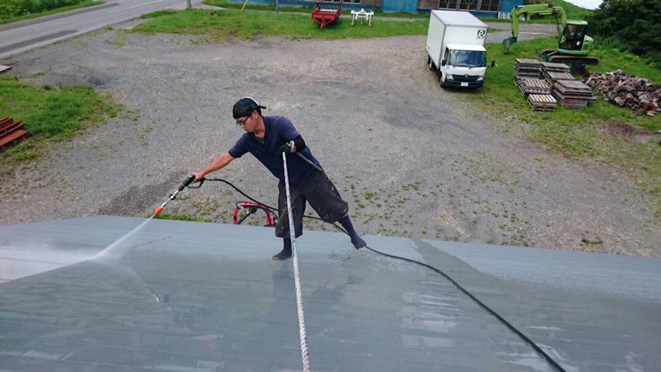 掃除の様子。命綱一本で屋根を掃除する。